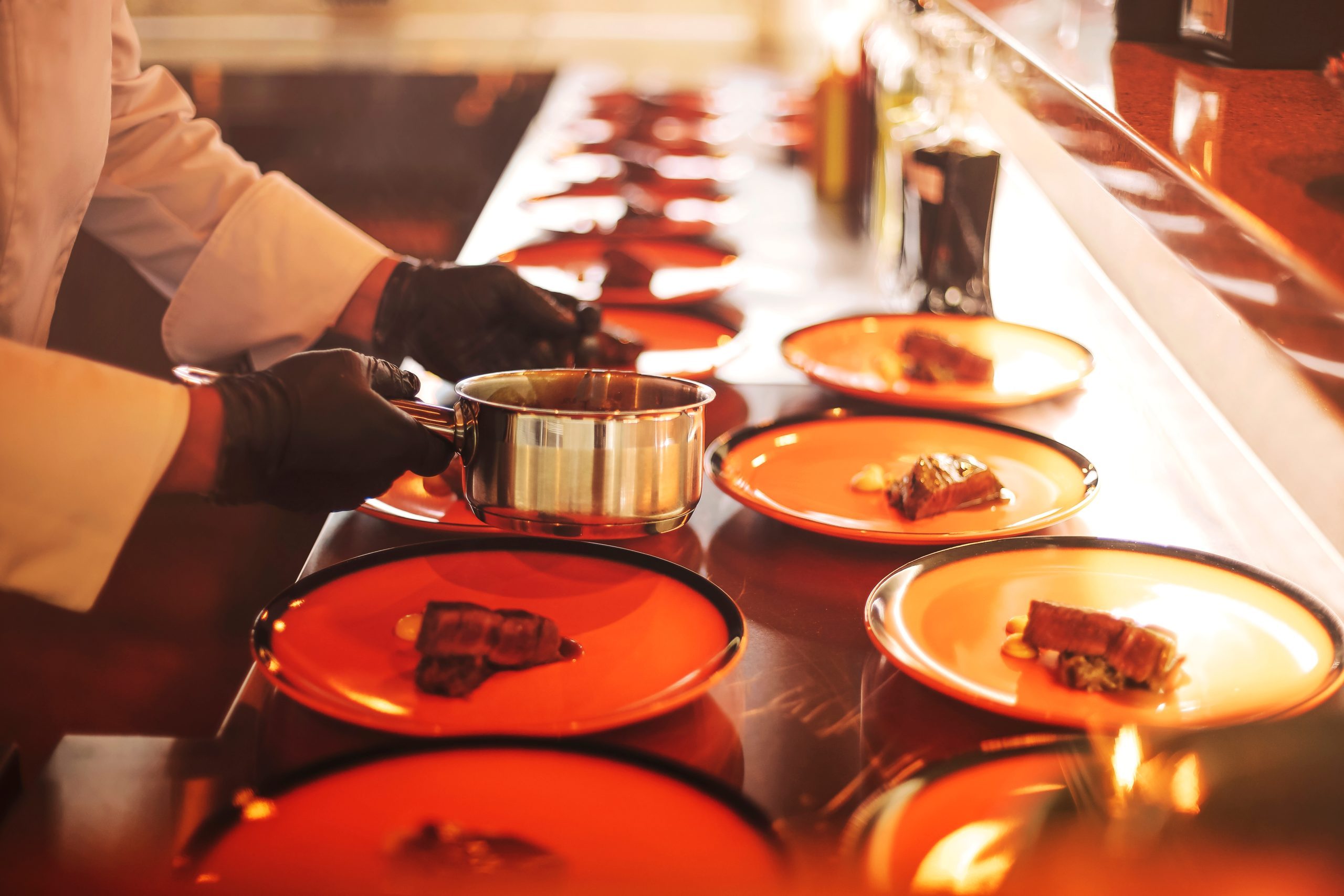 Chef in a restaurant servicing meat with iron pot